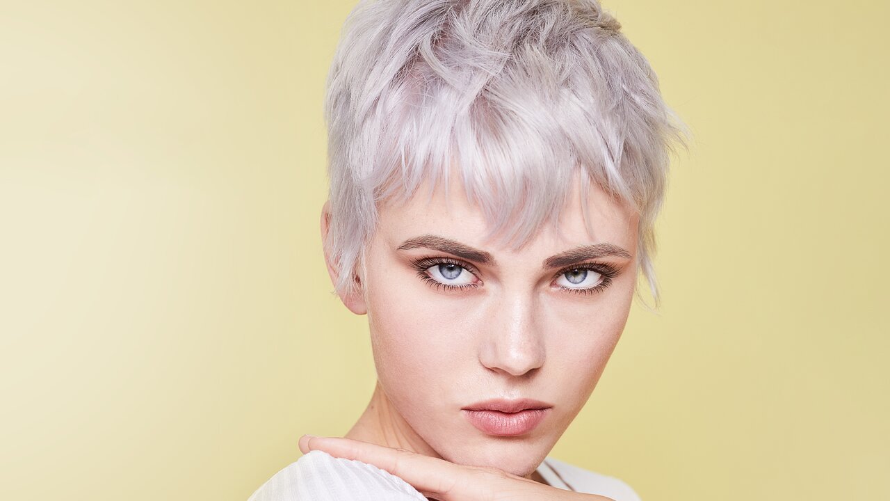 Silbershampoo hilft gegen unschönen Gelbstich und sorgt für ein schönes kühles Blond Portrait einer schönen Fraue mit kurzen Haaren und einer Pixie-Frisur in der Trendhaarfarbe Eisblond