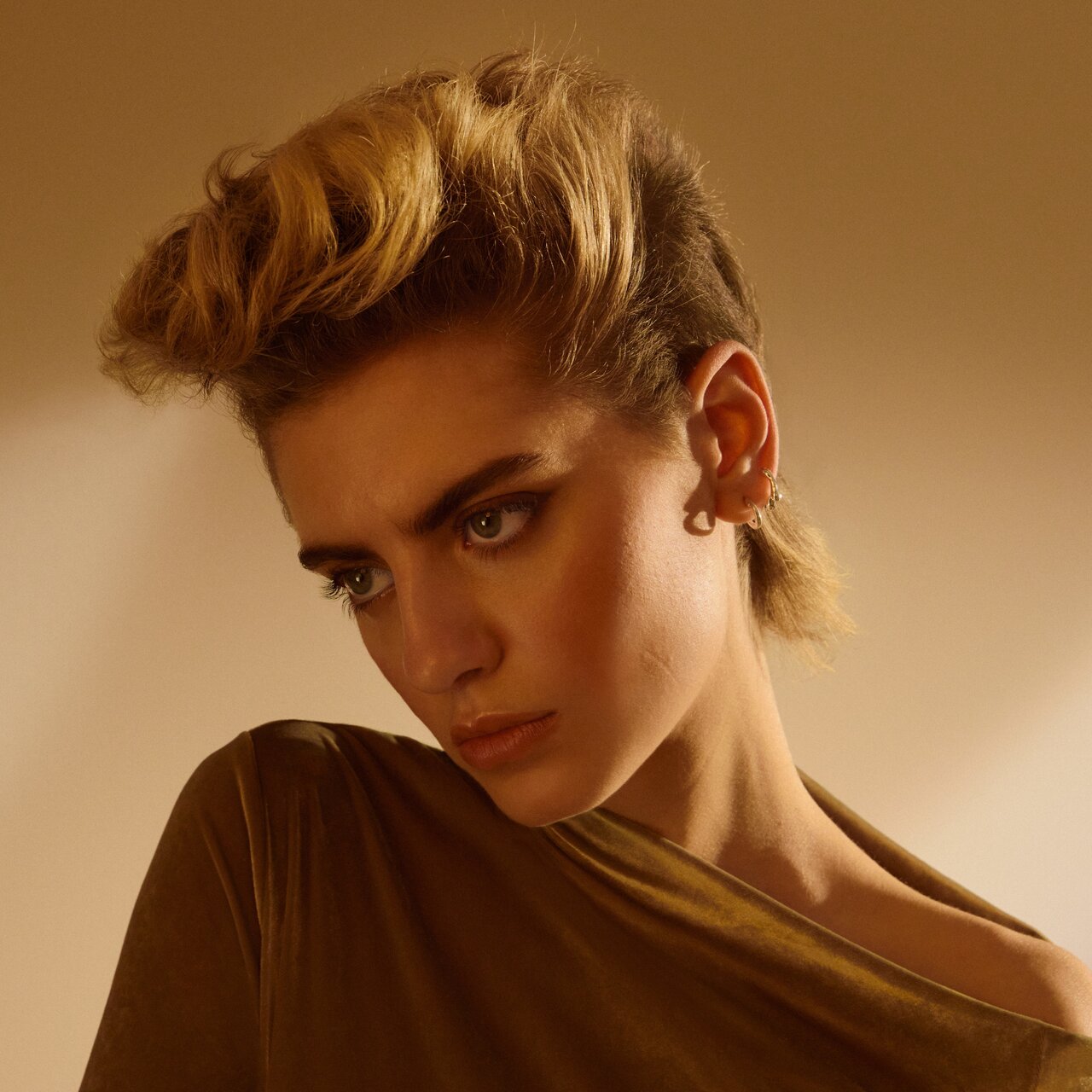 Porträt einer jungen Frau. Sie trägt einen hochgestylten Kurzhaarschnitt mit gekürzten Seiten