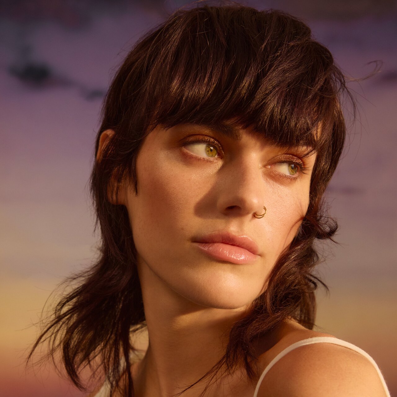 Porträt einer jungen Frau, die einen brünetten Mullet mit sanften Locken trägt