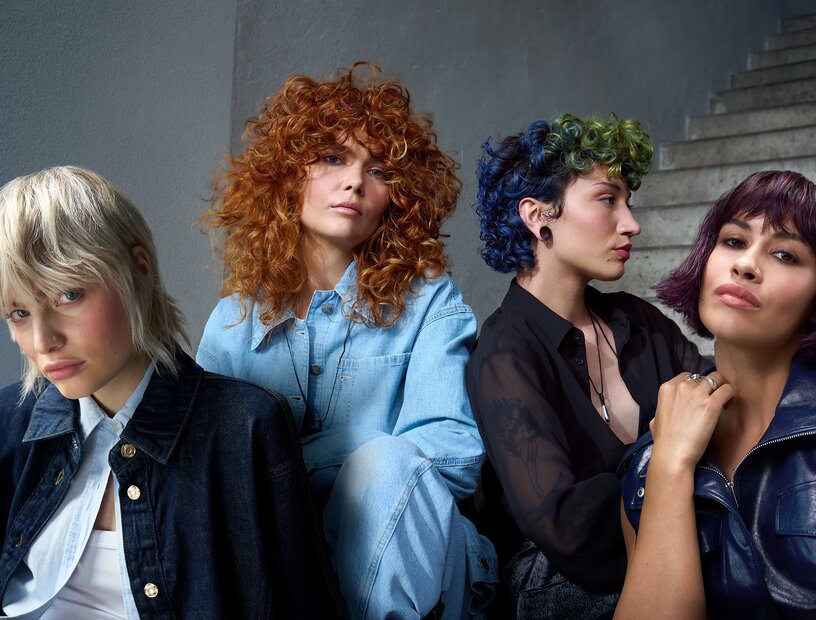 Vier Models mit unterschiedlichen, farbintensiven Frisuren posieren modern inszeniert vor einer Treppe.