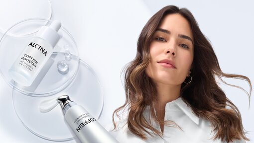 Close-up des ALCINA Coffein Augenfluids sowie Coffein Boosters neben einer lächelnden jungen Frau mit leicht welligen braunen Haaren die offen über ihre Schulter fallen