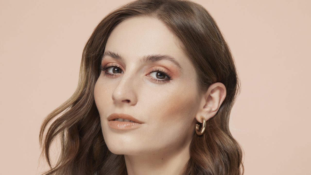 Portrait einer hübschen Frau mit braunen Haaren und Lidschatten in Bronze, die den Make-up Trend Bronzing Eyes im Sommer 2023 präsentiert