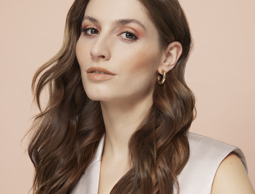 Portrait einer hübschen Frau mit braunen Haaren und Lidschatten in Bronze, die den Make-up Trend Bronzing Eyes im Sommer 2023 präsentiert