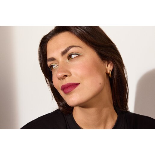 Schöne junge Frau mit braunen Haaren im Profil, der Fokus liegt auf den kräftig geschminkten Lippen in Beerenton, die den Make-up-Trend Matte Cherry Lips repräsentieren