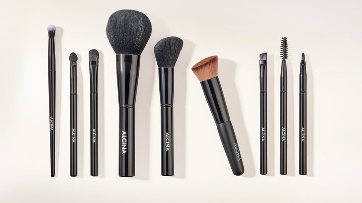 ALCINA Make-up-Zubehör mit verschiedenen Pinseln und Wimpernbürste ordentlich nebeneinander angeordnet.