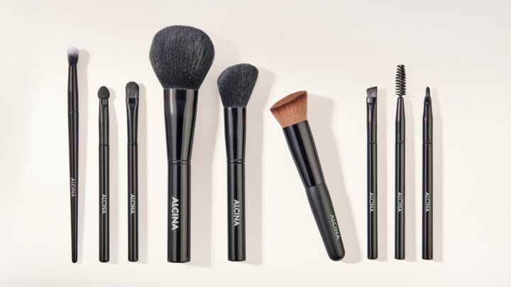 ALCINA Make-up-Zubehör mit verschiedenen Pinseln und Wimpernbürste ordentlich nebeneinander angeordnet.