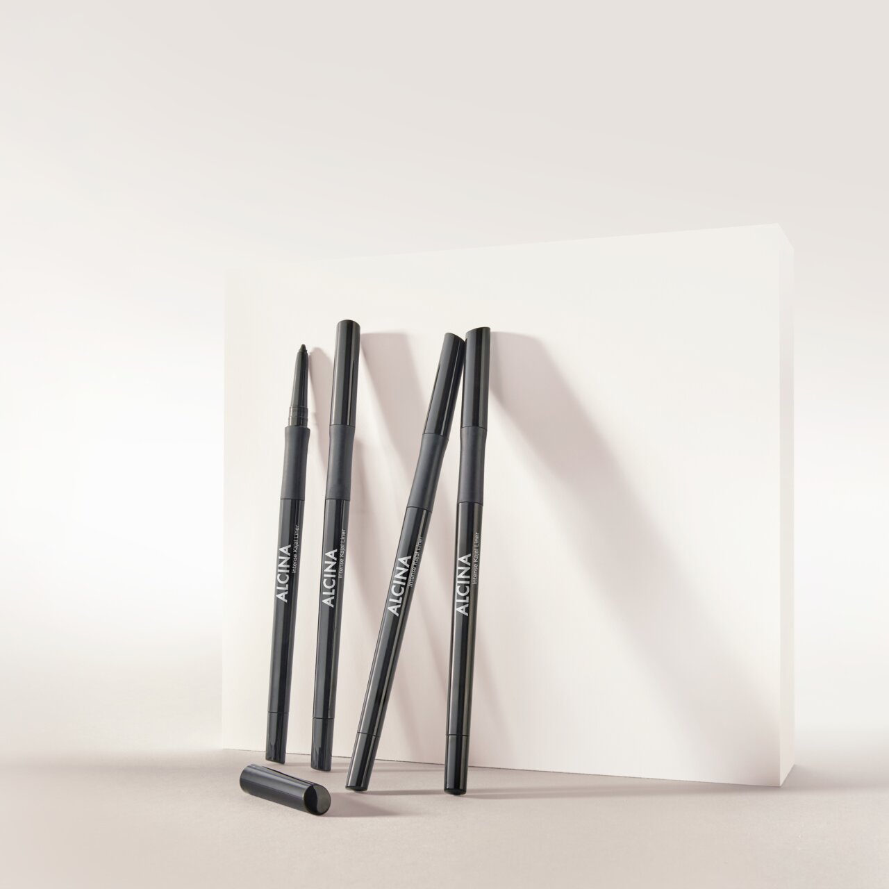ALCINA Intense Kajal Liner in elegantem schwarzen Stiftdesign, stehend und liegend vor hellem Hintergrund arrangiert, ideal für präzise und intensive Augen-Make-up-Looks.