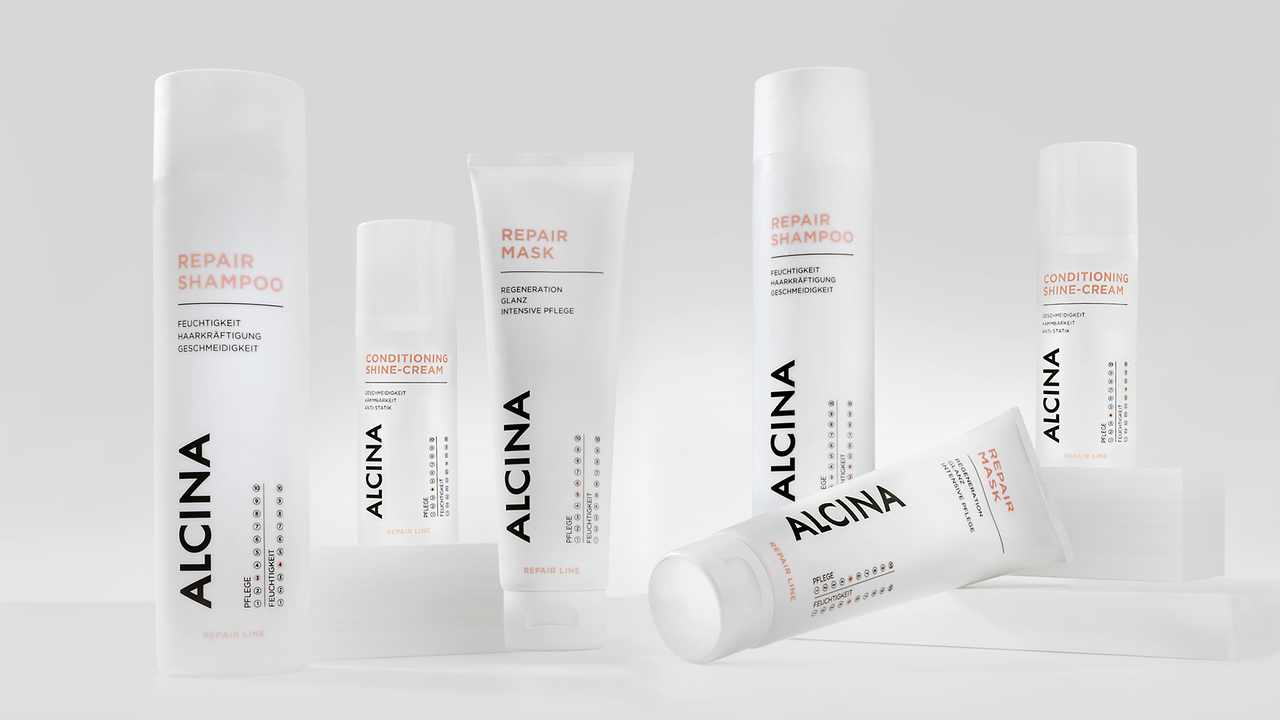 ALCINA Repair-Haarpflegeserie mit Repair-Shampoo und Maske in weißem, cleanem Verpackungsdesign, modern auf heller Fläche arrangiert.