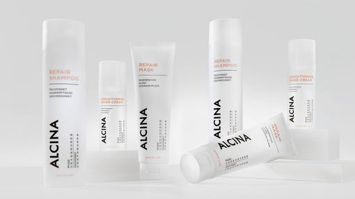 ALCINA Repair-Haarpflegeserie mit Repair-Shampoo und Maske in weißem, cleanem Verpackungsdesign, modern auf heller Fläche arrangiert.