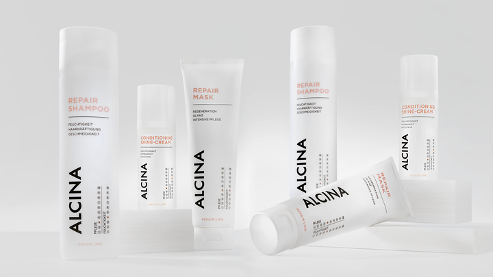 ALCINA Repair-Haarpflegeserie mit Repair-Shampoo und Maske in weißem, cleanem Verpackungsdesign, modern auf heller Fläche arrangiert.
