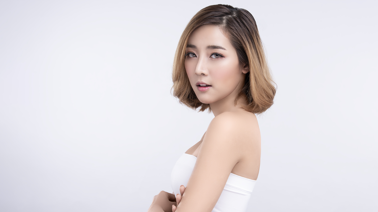 Auch bei einem Bob kann die Ombre Haarfärbetechnik mit ALCINA Haarfarben sehr elegant wirken Halbportrait einer Frau im weißen, ärmellosen Top mit ombré-gefärbtem dunkelblondem Bob-Haarschnitt