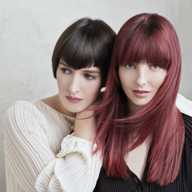 Farbshampoos sind in vielen Farbtönungen erhältlich, auch für kräftiges Braun und dunkles Rot Portrait zweier Frauen, die nebeneinander stehen: eine mit einer Langhaarfrisur in dunklem Rot, die andere mit einem brünetten Bob