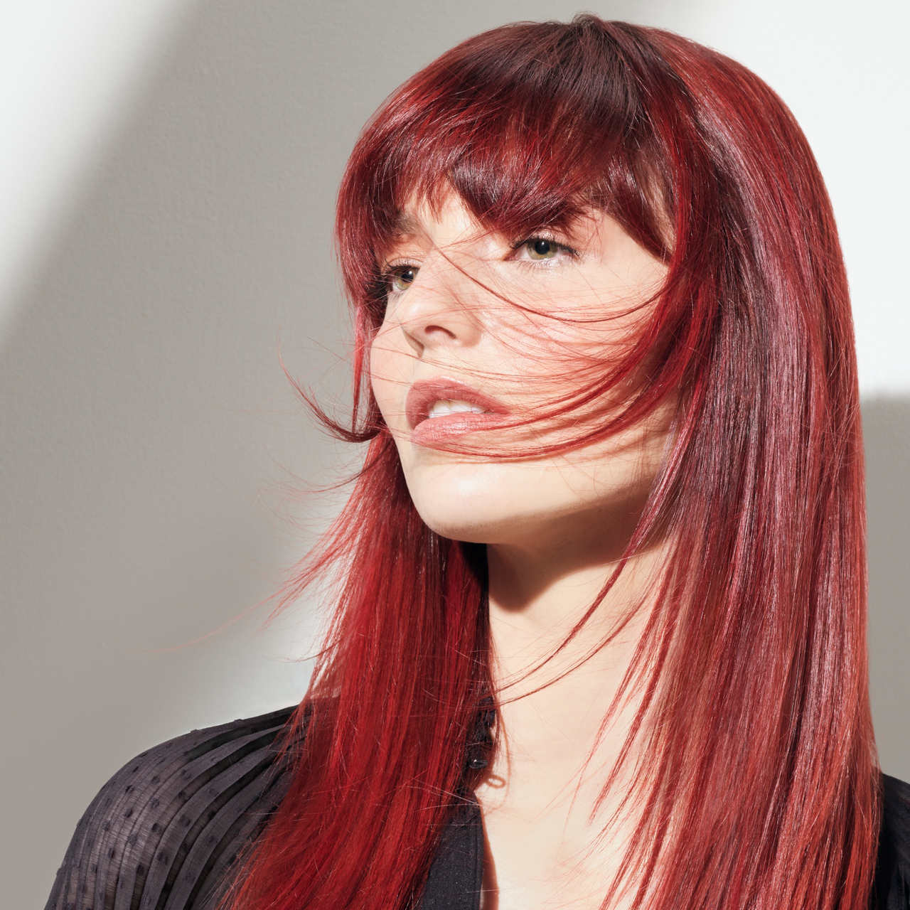 Portrait einer jungen Frau mit langen, glatten Haaren in einem leuchtenden Rot
