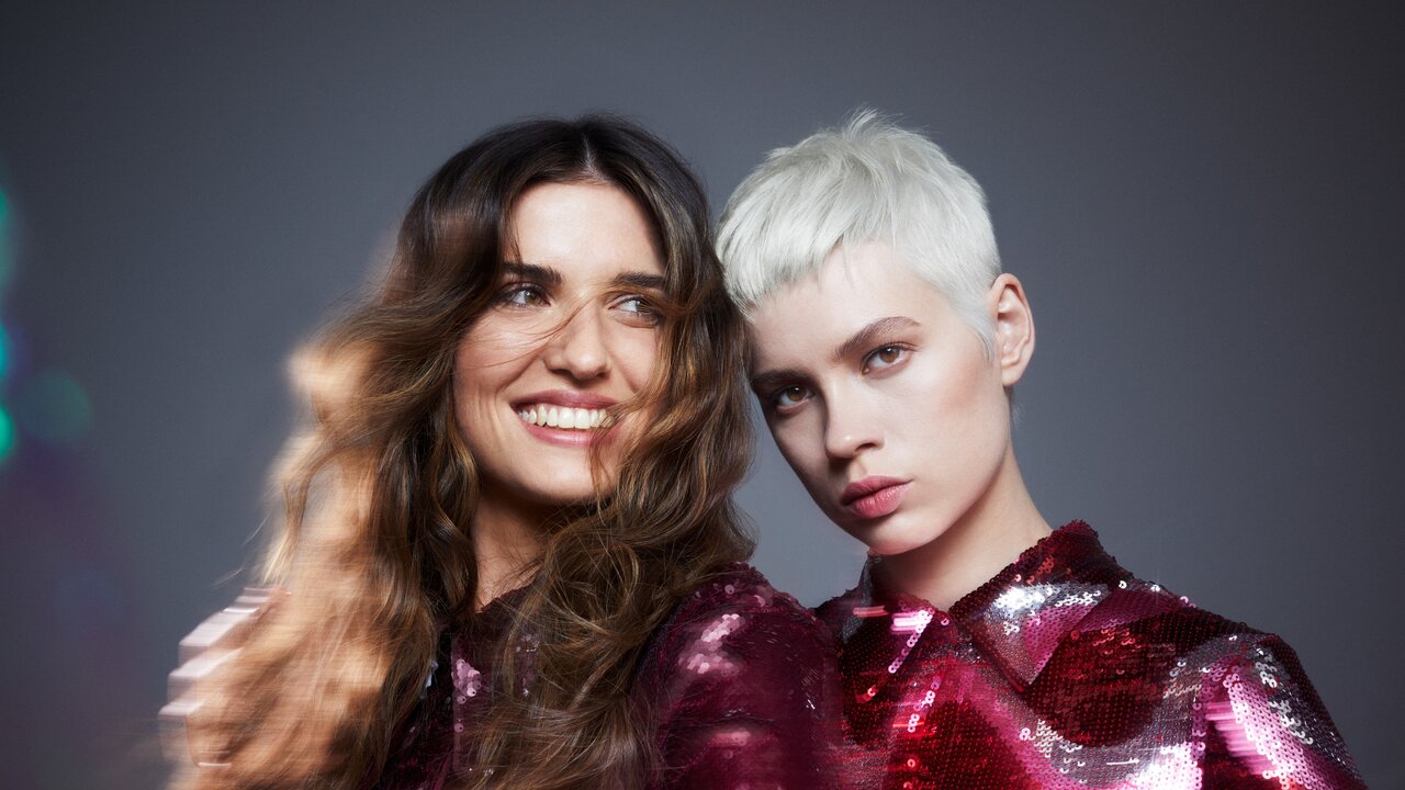 Porträt von zwei schönen jungen Frauen, die die Frisuren und Haarfarben Trends 2024 für kurze und für lange Haare präsentieren