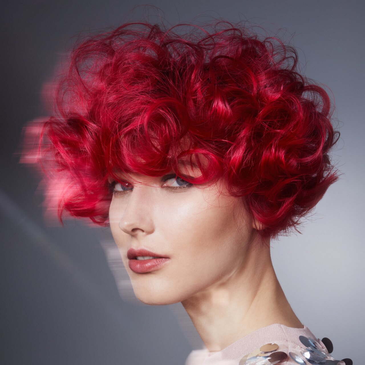 Porträt einer schönen jungen Frau mit mittellangen lockigen Haaren in der Trend-Haarfarbe 2024 Vibrierendes Rot