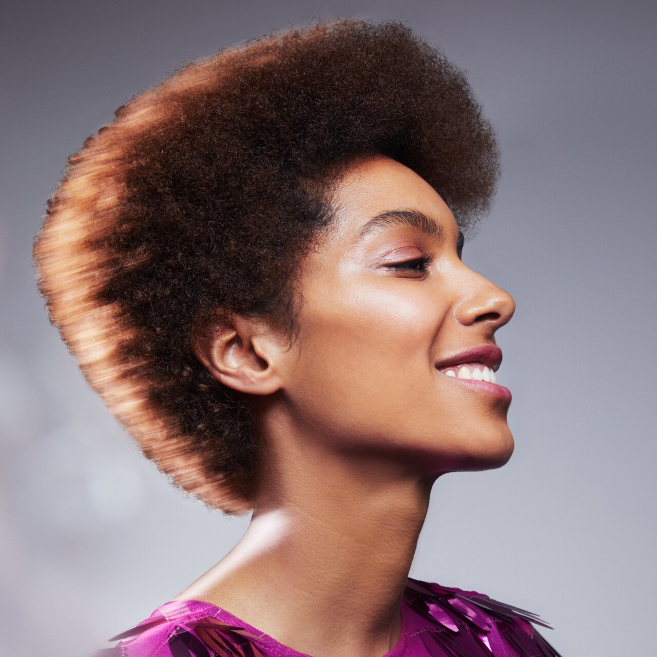 Porträt einer schönen jungen Frau mit mittellangem krausem Haar, das zu einer Afro Frisur gestylt wurde