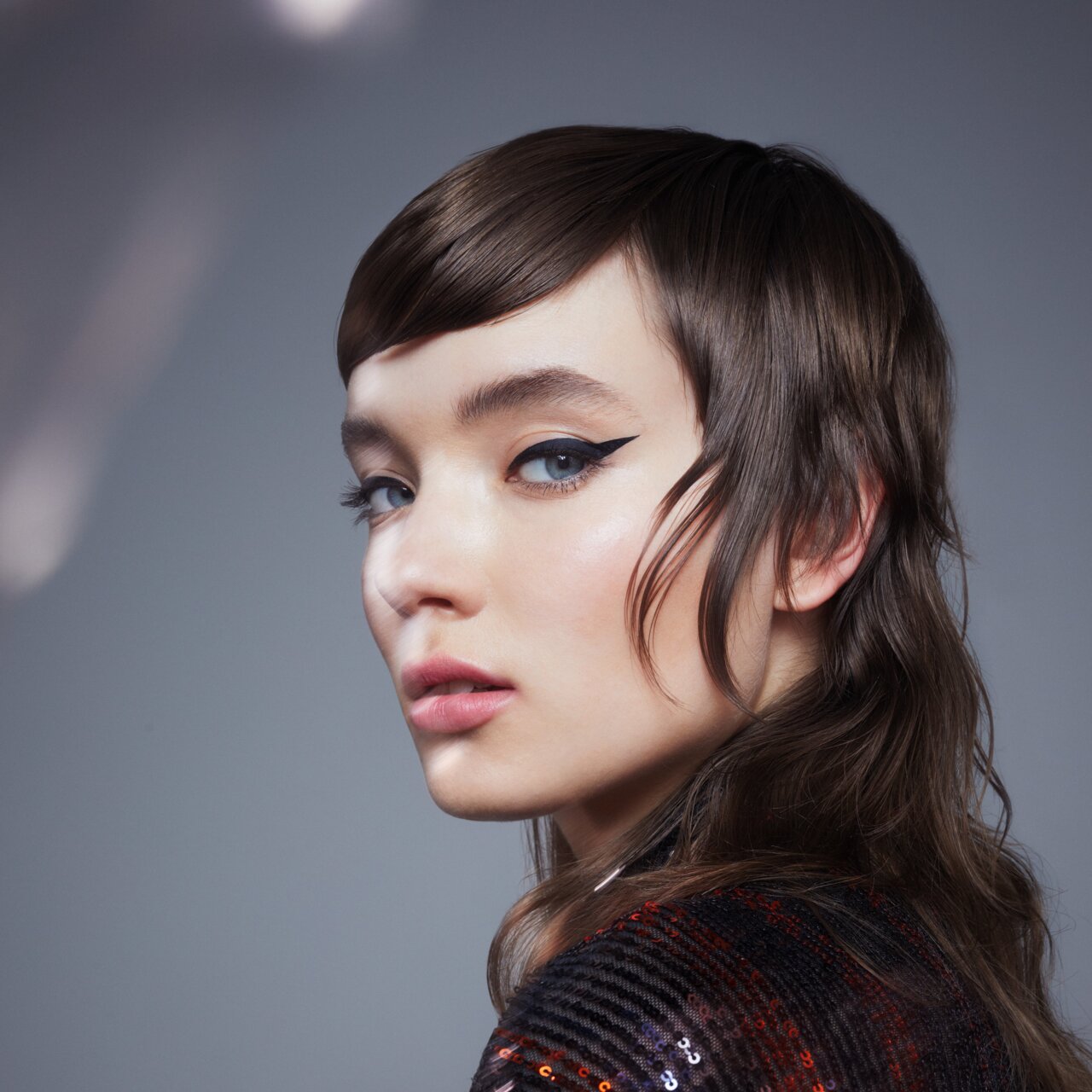 Porträt einer schönen jungen Frau, die den Frisuren Trend 2024 Soft Mullet, ein Vokuhulia mit sanften Stufen, präsentiert