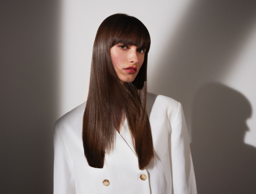 Schöne, junge Frau, deren dunkelbraune, lange Haare glatt und glänzend offen über Ihre Schulter fallen. 