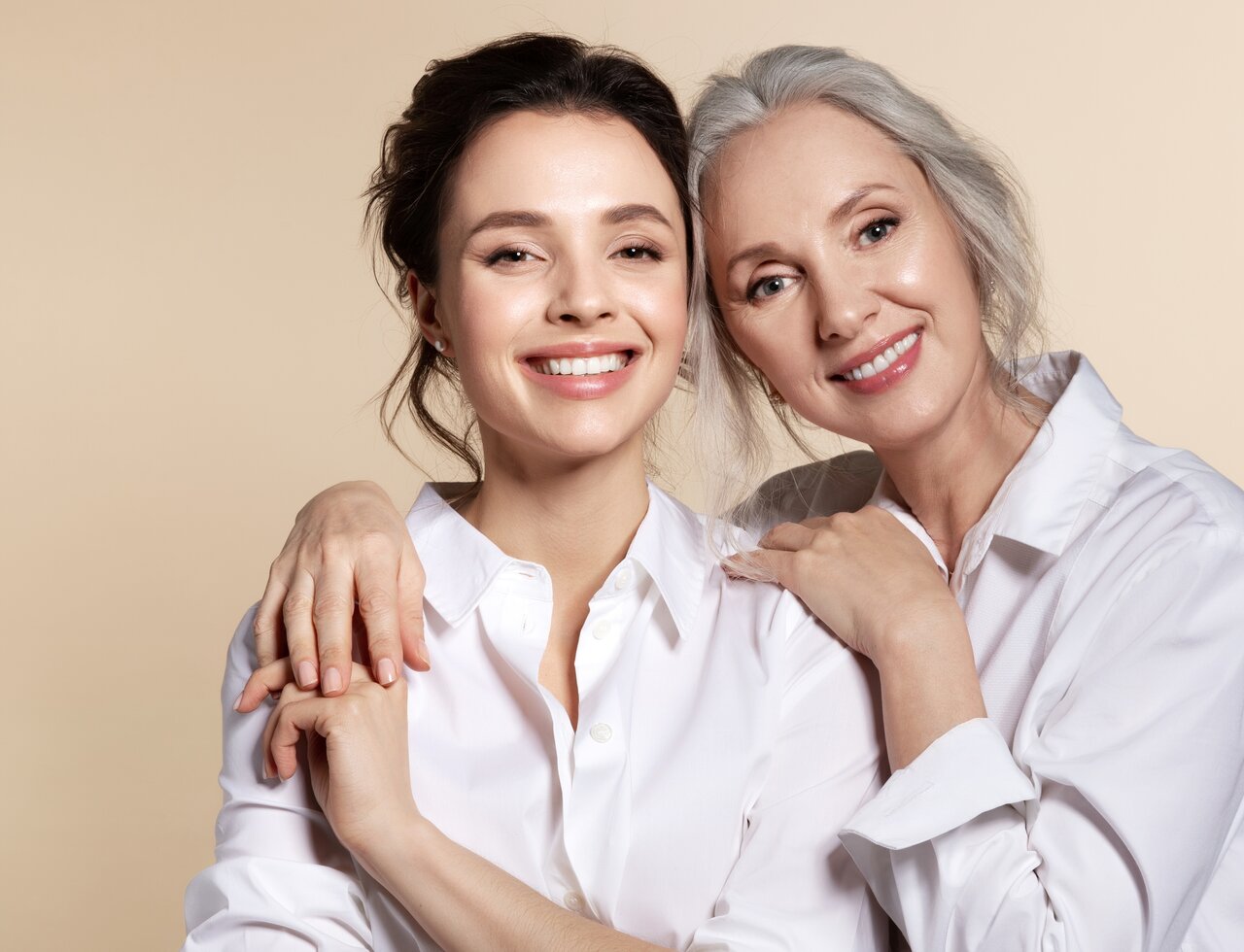 Schöne Frau um die 60 Jahre mit gepflegter Haut steht neben einer jüngeren Frau als Sinnbild für die richtige Gesichtspflege für jedes Alter bei reifer Haut