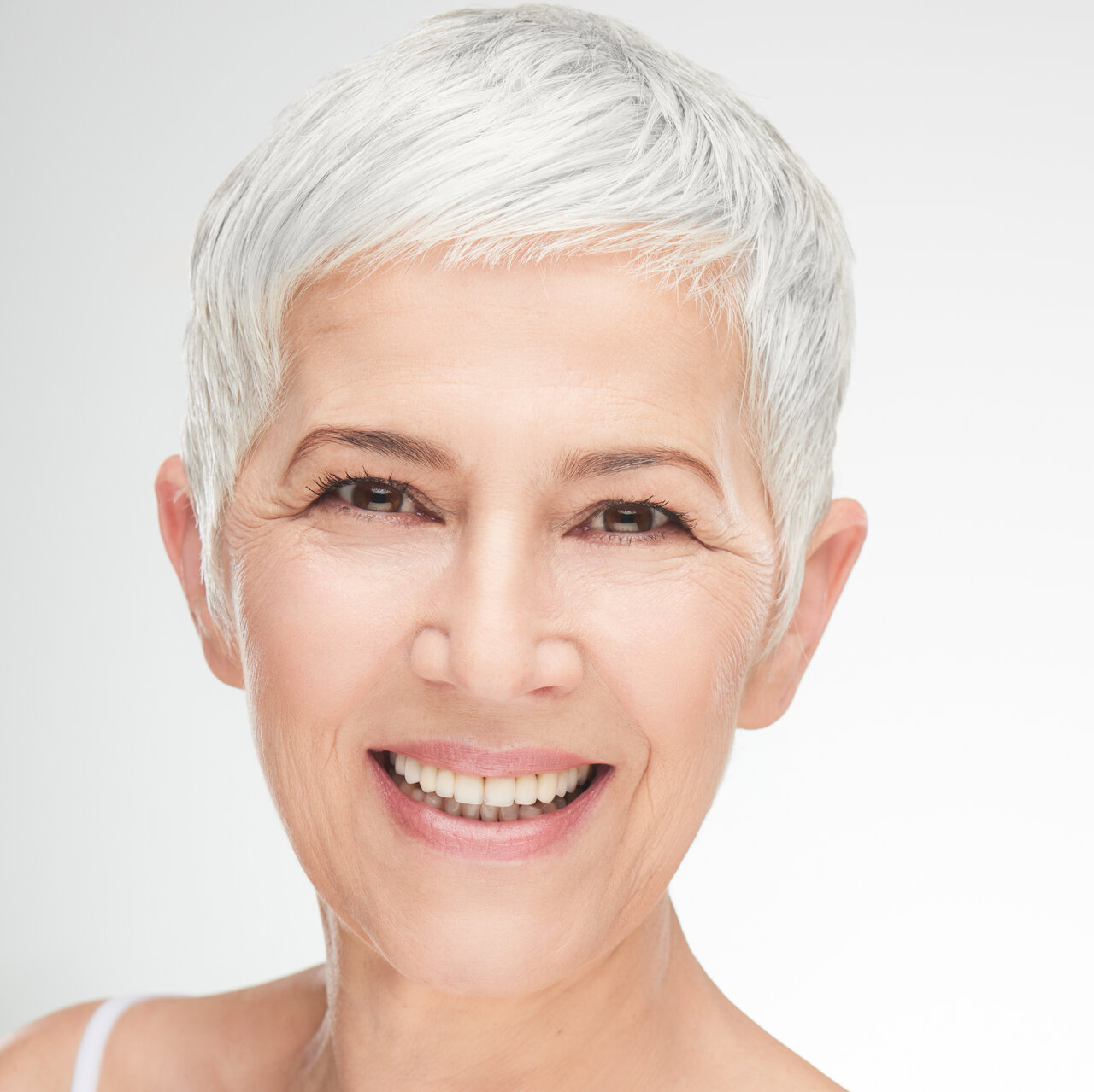 Portrait einer reifen schönen Frau mit grauen Haaren und dezentem rosa Lippenstift 