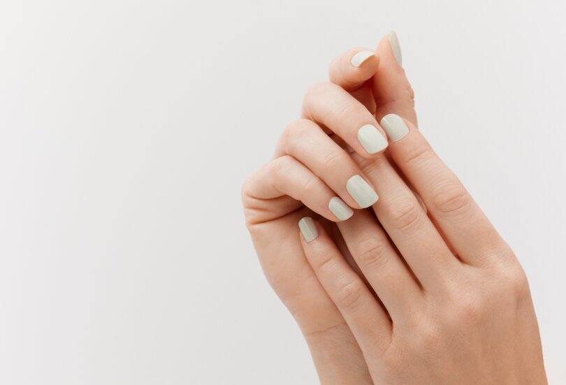 Nahaufnahme von zwei schönen Händen einer jungen Frau mit mintfarben lackierten Nägeln als Sinnbild für den Make-up Trend Bright Nails im Frühling Sommer 2024