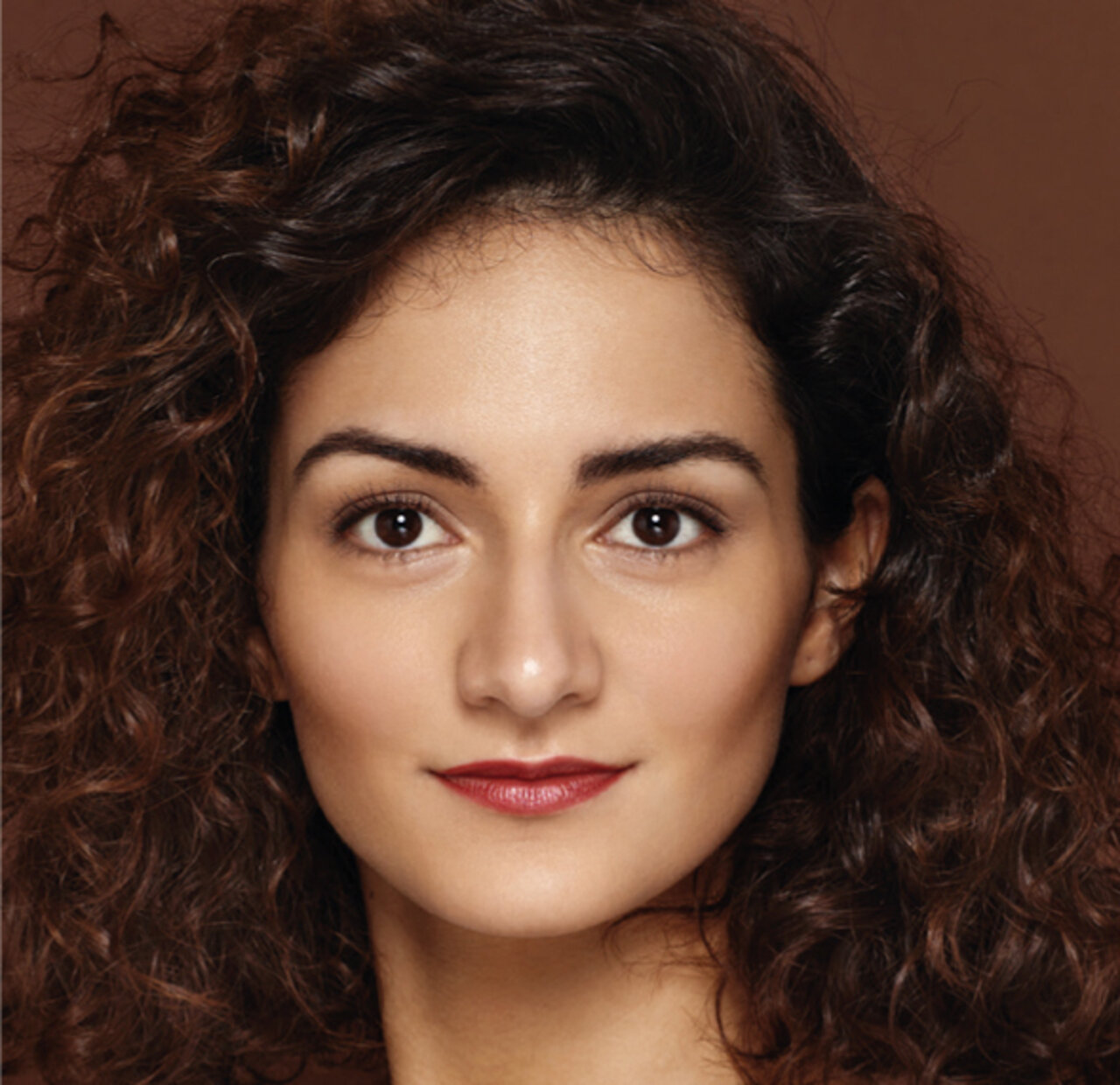 Portrait einer jungen Frau mit orangerotem Lippenstift, die einen mediterranen Typ mit dunklen Haaren und warmen Hauttyp repräsentiert