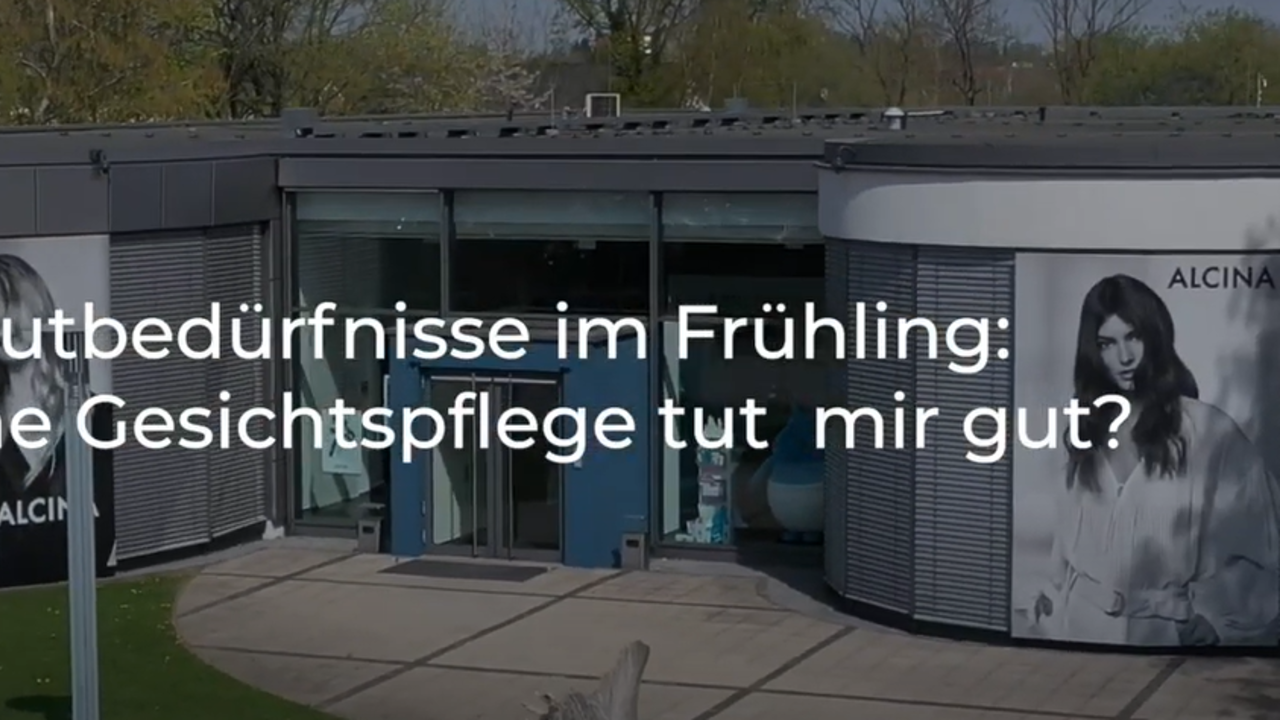  Text "Hautbedürfnisse im Frühling: Welche Gesichtspflege tut mir gut?"  vor halbtransparentem Hintergrund. Der Hintergrund zeigt ein modernes Gebäude mit großer Glasfronten, die mit großen Modepostern der Marke ALCINA behangen sind. Bäume und Grün umgeben das Gebäude.