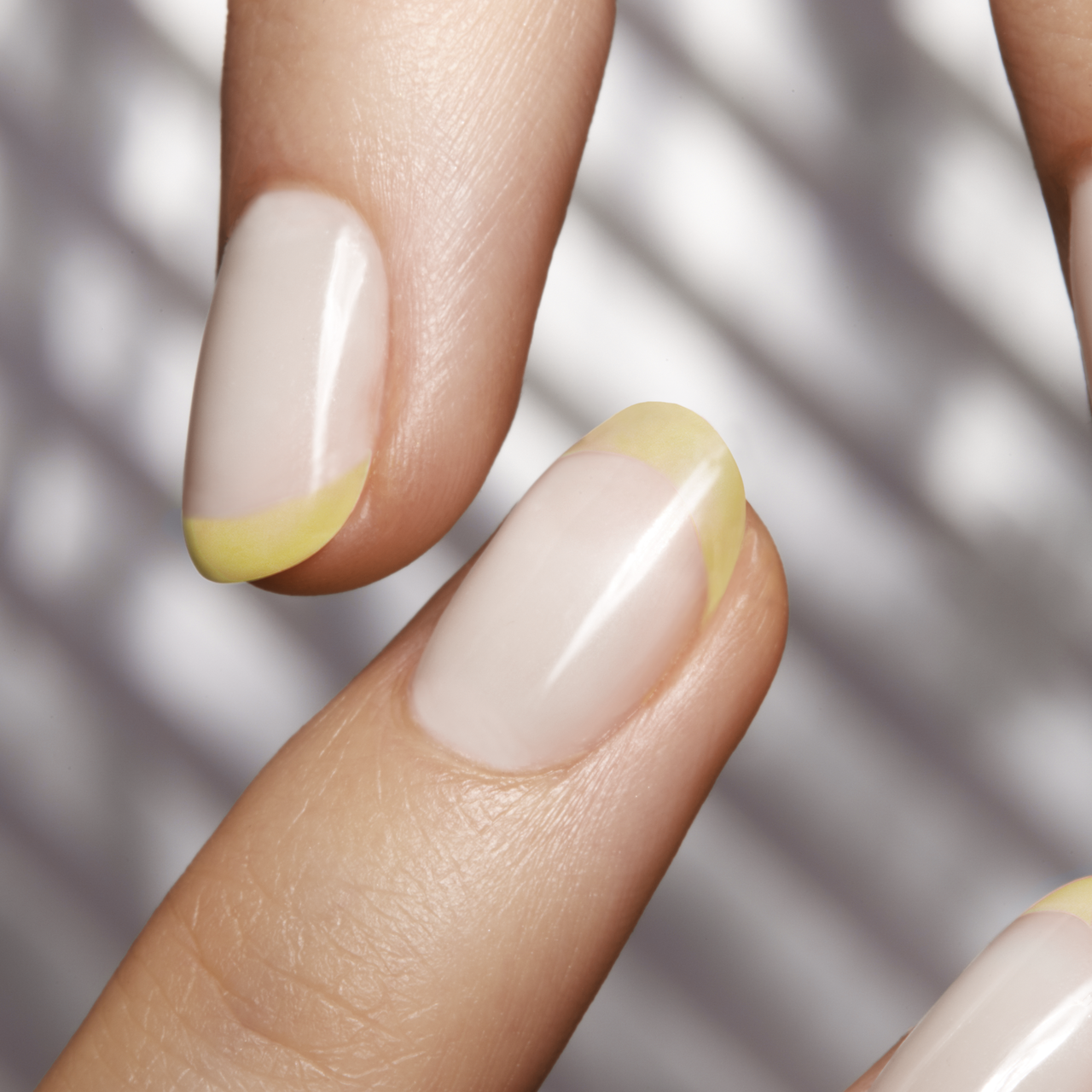Nahaufnahme von natürlich lackierten Nägeln mit gelb lackierter Nagelspitze im angesagten Sommer Make-up Trend French Tip Nails