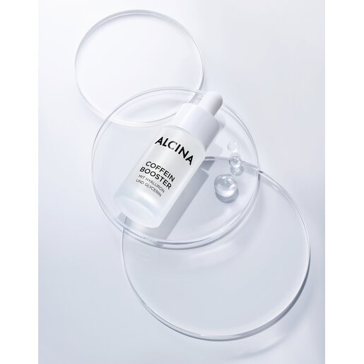 Produktabbildung Glasflasche mit Pipette ALCINA Coffein Booster liegend auf runden Glasplättchen auf grauem Untergrund