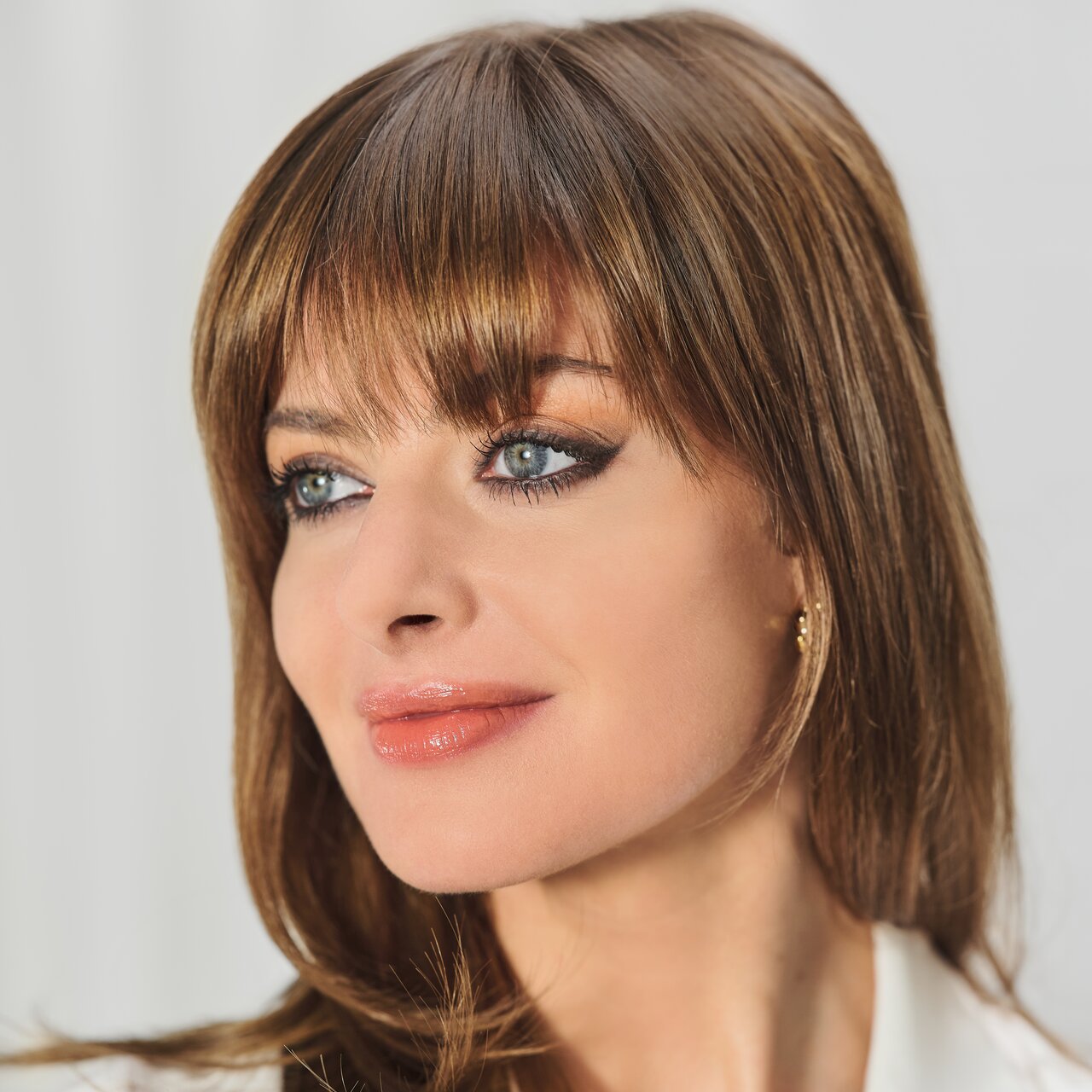 Gesicht einer jungen Frau mit intensiv geschminkten Augen und glänzenden Lippen, die den Make-up Trend Bronzing Eyes im Sommer 2023 präsentiert