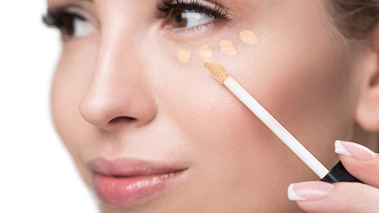 ALCINA make-up Concealer – ideal zum Abdecken von Augenringen, dunklen Schatten und kleinen Rötungen Nahaufnahme einer sich schminkenden Frau, die sich mit einem Applikator kleine Concealer-Punkte unter das Auge setzt
