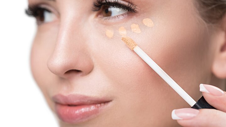 ALCINA make-up Concealer – ideal zum Abdecken von Augenringen, dunklen Schatten und kleinen Rötungen Nahaufnahme einer sich schminkenden Frau, die sich mit einem Applikator kleine Concealer-Punkte unter das Auge setzt