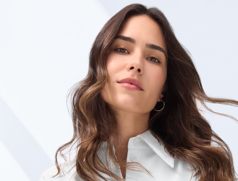 Ein frischer, rosiger Teint und lange, gesunde Haare – der Power-Wirkstoff Coffein macht’s möglich Schöne Frau mit rosigem Teint und langen braunen Haaren lächelt in die Kamera als Sinnbild für die Wirkung von Coffein-Hautpflege und Coffein für die Haare