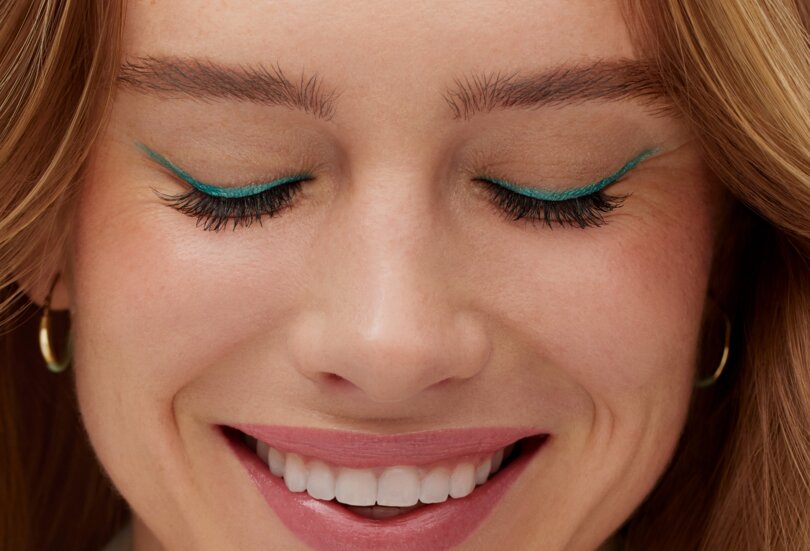 Nahaufnahme einer schönen jungen Frau mit extravagantem Lidstrich in der Trendfarbe Türkis als Sinnbild für den Make-up Trend Turquoise Eyes im Frühling Sommer 2024